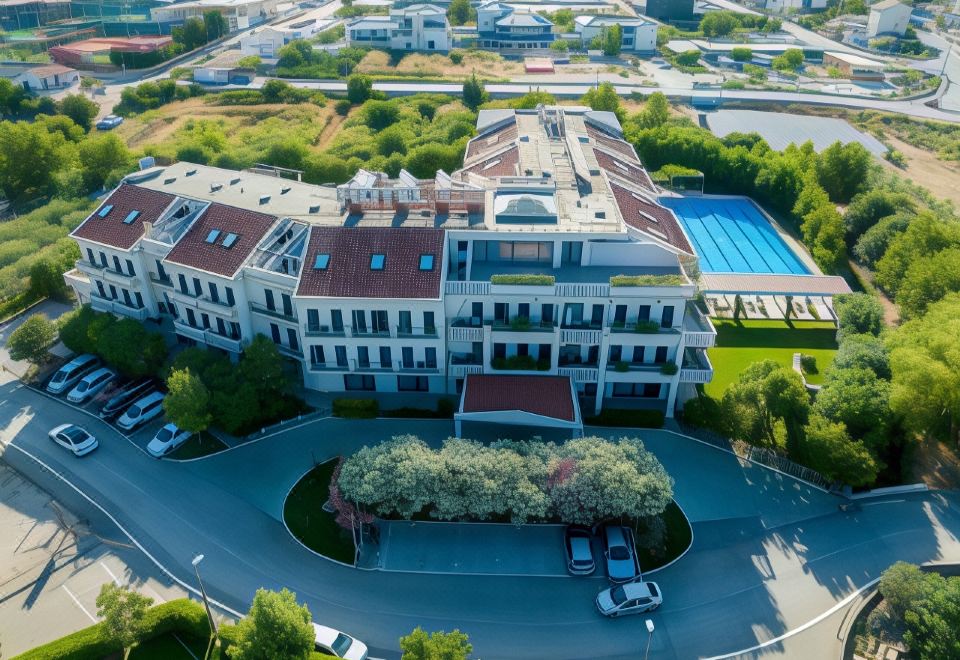 aerial view of a large white building surrounded by trees and a pool , with cars parked in front at Hotel President Solin