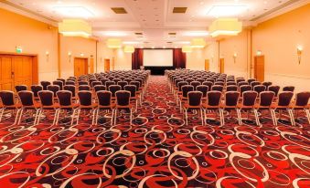 a large conference room with rows of chairs arranged in a semicircle , and a projector screen mounted on the wall at The Park Royal Hotel & Spa