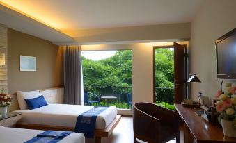 a modern hotel room with two beds , a window offering a view of trees , and a desk near the window at Rumah Batu Boutique Hotel