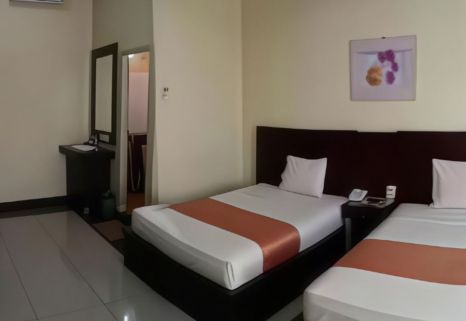 a modern hotel room with two beds , a desk , and an air conditioner , decorated in neutral colors at Jazz Hotel Palu