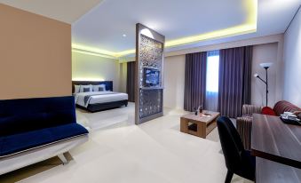 a modern hotel room with a bed , tv , and couch , as well as a bathroom with a shower at Hotel Neo Eltari - Kupang by Aston