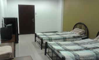 a room with two beds , one on the left side and the other on the right side of the room at Thanarom Place