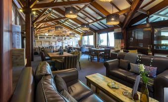 a spacious , well - lit restaurant with wooden ceiling beams , leather couches , and dining tables , as well as several chairs and comfortable seating at Middletons