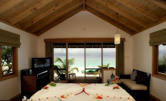 a luxurious bedroom with a large bed , a tv , and a view of the ocean at Kuredu Island Resort & Spa