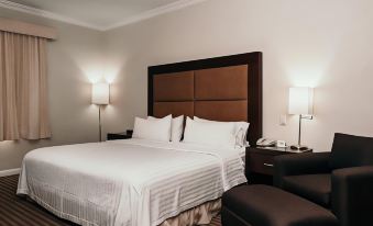 a large bed with white sheets and pillows is in a room next to a nightstand at Holiday Inn Express Durango