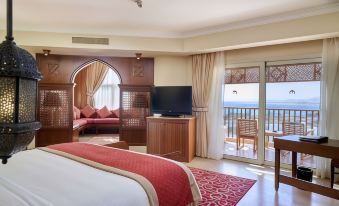a luxurious hotel room with a king - sized bed , a flat - screen tv , and a balcony overlooking the ocean at Kempinski Hotel Soma Bay
