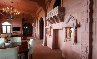 a large room with a dining table and chairs , a fireplace , and a painting on the wall at Jodha Bai Retreat