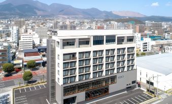 "an aerial view of a modern building with the word "" hotel "" written on it , located in a city with mountains in the background" at Rex Hotel Beppu