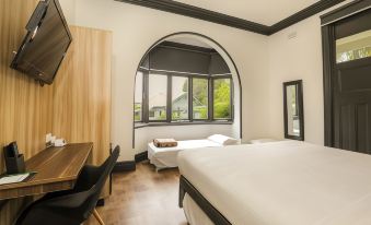 a modern hotel room with a large bed , desk , and window overlooking the city , providing a comfortable and modern environment at Glenferrie Lodge