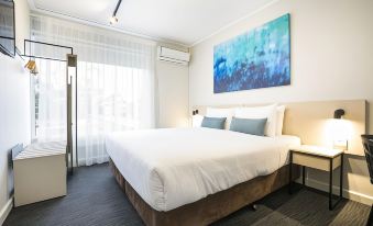 a large bed with white linens is situated in a room with a window and an air conditioner at Nightcap at Playford Tavern