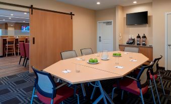 a conference room with a long table , chairs , and various items on the table , including wine glasses and apples at TownePlace Suites Grand Rapids Airport