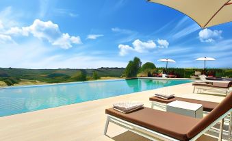 a large pool with several lounge chairs and umbrellas is overlooking a valley , providing a serene view of the surrounding landscape at Villa le Calvane