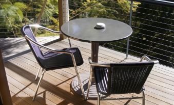 a wooden deck with two black chairs and a small round table , providing a comfortable outdoor seating area at Tambaridge Bed & Breakfast