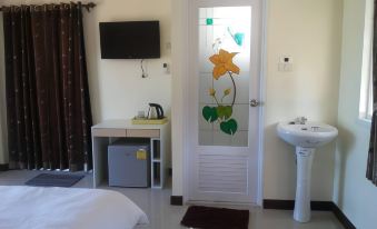 a small room with a bed , a sink , and a tv . also a door with a stained glass design at Lomtalay Resort Trat