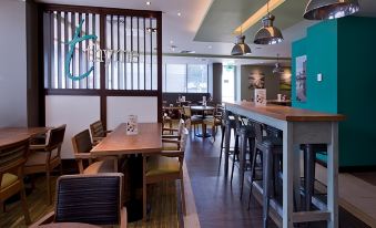 a restaurant with wooden tables and chairs , a bar area , and hanging lights on the ceiling at Premier Inn Oban