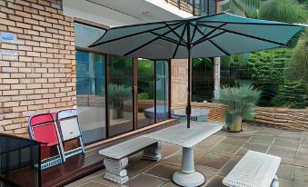 a patio with a dining table , benches , and an umbrella , surrounded by glass walls and brick at Hidden Inn