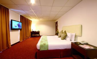 a hotel room with a large bed , a flat - screen tv , and a desk area at Jewels Hotel