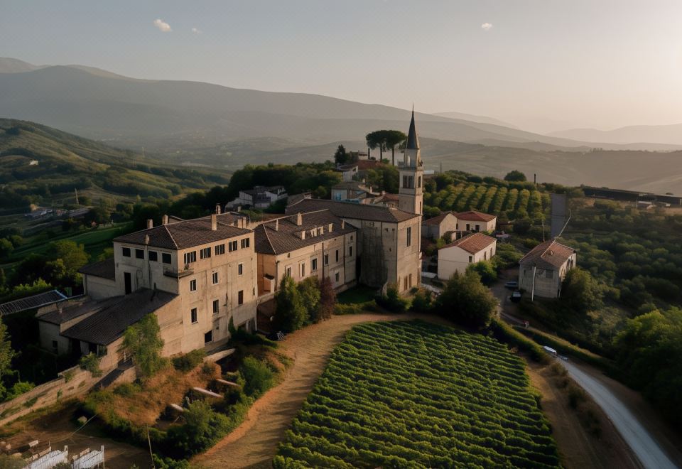 aerial view of a large stone building surrounded by green fields and vineyards , with mountains in the background at Castello di Semivicoli