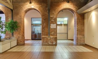 a brick building with an arched doorway , surrounded by a waiting room and a check - in area at Hotel Moco Valleyfield