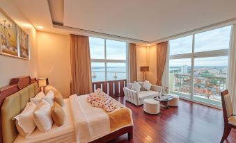 a luxurious hotel room with a large window overlooking the ocean , featuring a comfortable bed , a couch , and a dining table at Lbn Asian Hotel
