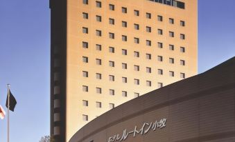 "a large , modern hotel building with a curved design and the words "" new world city hotel "" written in white letters" at Route Inn Grantia Komaki