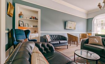 a living room with a black leather couch , a black chair , and a television mounted on the wall at Oakhill