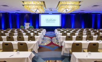 a large conference room with rows of tables and chairs , a projector screen at the front at Kahler Grand Hotel