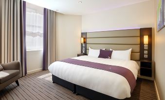 a large bed with a purple and white comforter is in a room with wooden floors at Premier Inn Oban