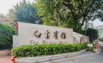 The entrance to a park is marked by large signs on both sides and is surrounded by trees at Baiyun Hotel