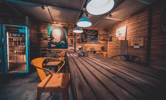 A room with wooden tables and chairs features an open concept kitchen along one wall at Poshpacker Flipflop Youth Hostel (Taikoo Li Chunxi Road Metro Station)