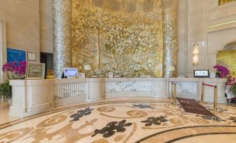 The lobby features a large wall adorned with gold and white marble, along with other decorative elements at Grand Metropark Guofeng Hotel, Tangshan