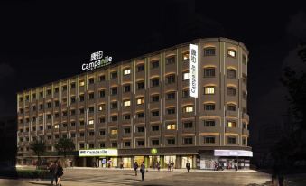 A night time lapse photo was taken of a large building with people walking in front at Campanile Hotel (Shanghai The Bund)