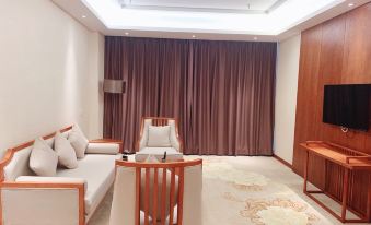 a living room with white furniture and a brown curtain , along with wooden furniture in the background at Sunshine Hotel