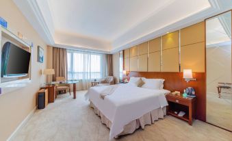 a large , well - made bed is the centerpiece of a hotel room with a balcony and a desk at Regency Hotel