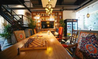 A wooden table is set in the center, adorned with chairs and books for playing games at POSHPACKER Local Tea Hostel