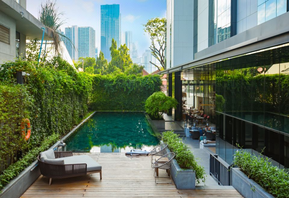 The luxury hotel offers a swimming pool with an outdoor lounge area and large windows that provide a scenic view of the city at HOMM Sukhumvit34 Bangkok - a brand of Banyan Group
