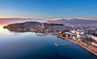 a city is nestled on the shore of a large body of water with mountains in the background at Villa Varosh