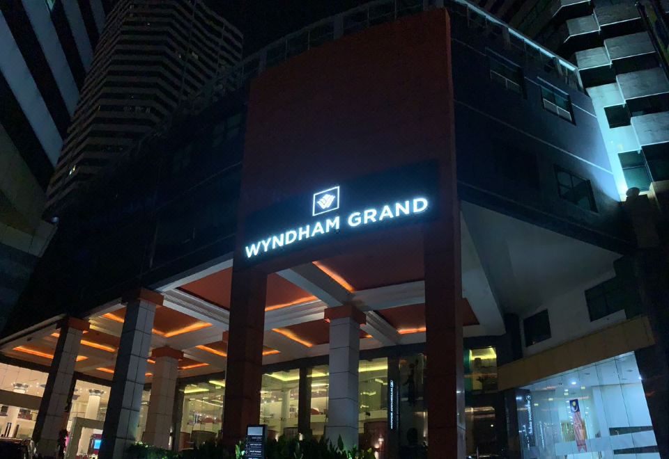 At night, the front entrance of a hotel is illuminated by a blue and white sign at Wyndham Grand Bangsar Kuala Lumpur(Formerly Pullman Kuala Lumpur Bangsar)