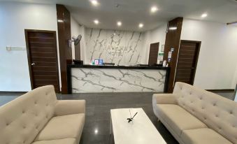 a modern office lobby with two couches , a coffee table , and a reception desk , all situated in front of a white marble wall at Havona Hotel - Kulai