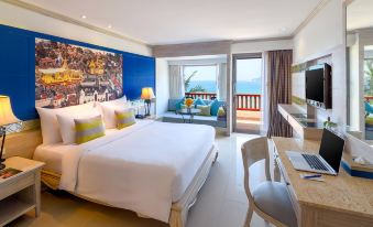 The hotel's living area features a bedroom with large windows, a balcony, and a double bed, providing a view of the filming at Novotel Phuket Resort