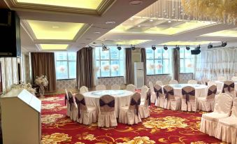 a large conference room with multiple round tables covered in white tablecloths , surrounded by chairs at Victoria International Hotel