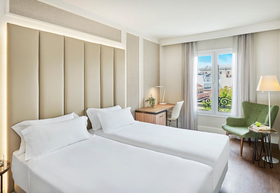 a hotel room with two white beds , one on the left and one on the right side of the room at NH Madrid Nacional