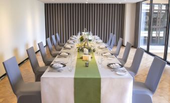A long table is set for an event, adorned with white chairs and green place mats in the center at The Westin Yilan Resort