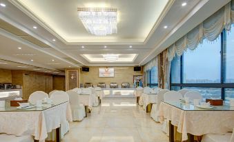 a large dining room with multiple tables covered in white tablecloths , creating a formal atmosphere at Vienna Hotel