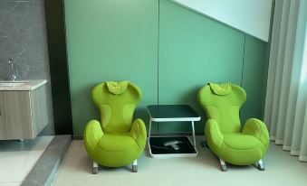 A room with two green chairs and an empty white table in the middle is another piece of furniture at European Style Theme Smart Hotel (Yiwu International Trade City District 2 and 3)