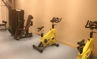 The room is equipped with various exercise equipment and features an indoor water pump located in the center on a tiled floor at Kaili Yade Hotel(Dongguan Huangjiang Jinyi Branch)