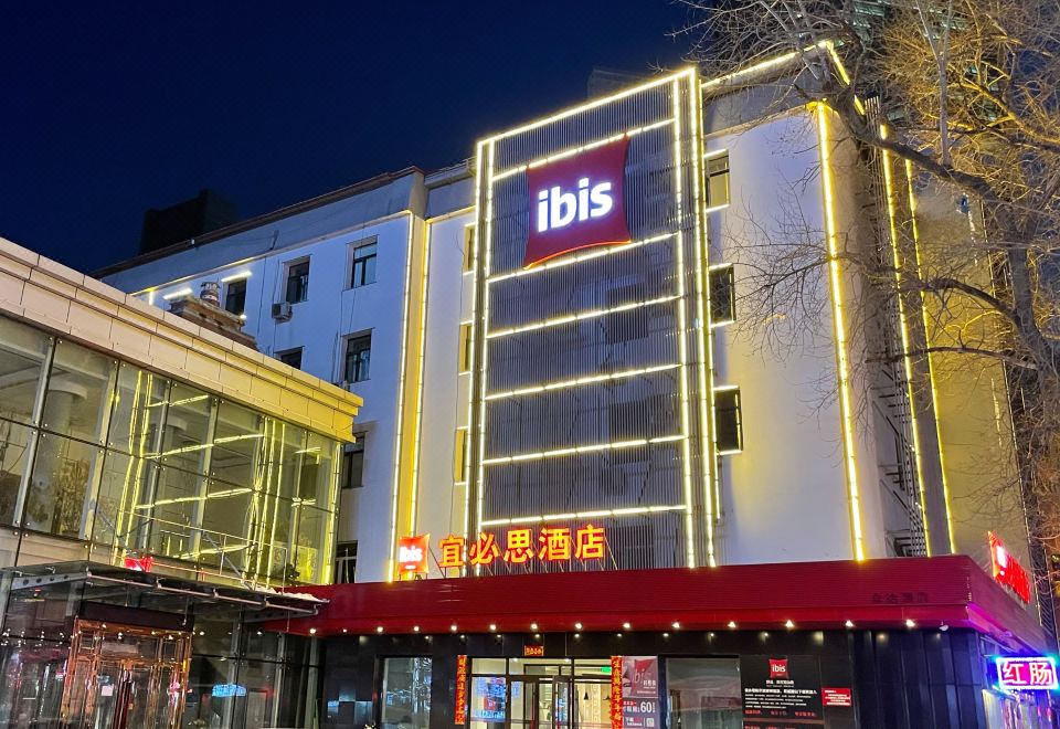"a large hotel building with a red sign that reads "" ibis "" prominently displayed on the front" at Ibis Hotel (Harbin Museum Subway Station)
