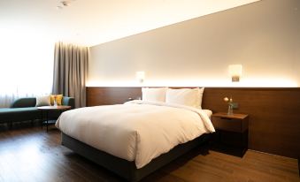 a large bed with white linens is in a room with wooden floors and a couch at The Marevo