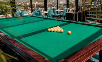 a green pool table set up in a room , surrounded by chairs and tables , with a view of the city outside at Hotel Old Town