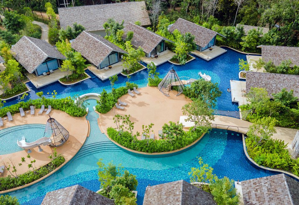 aerial view of a resort with a large pool surrounded by multiple buildings and a beach at Island Escape by Burasari